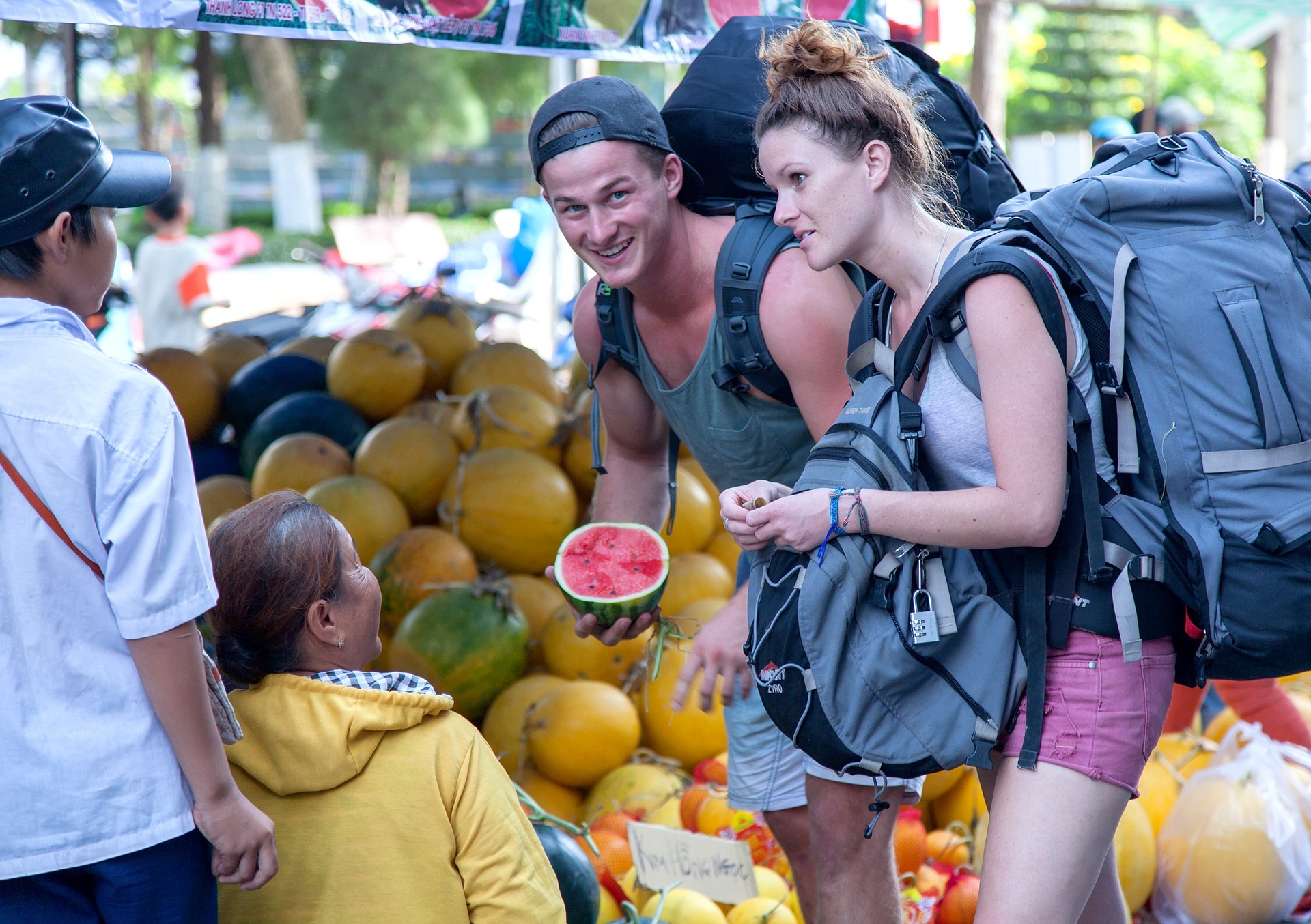 Casal de mochileiros comprando frutas em uma feira